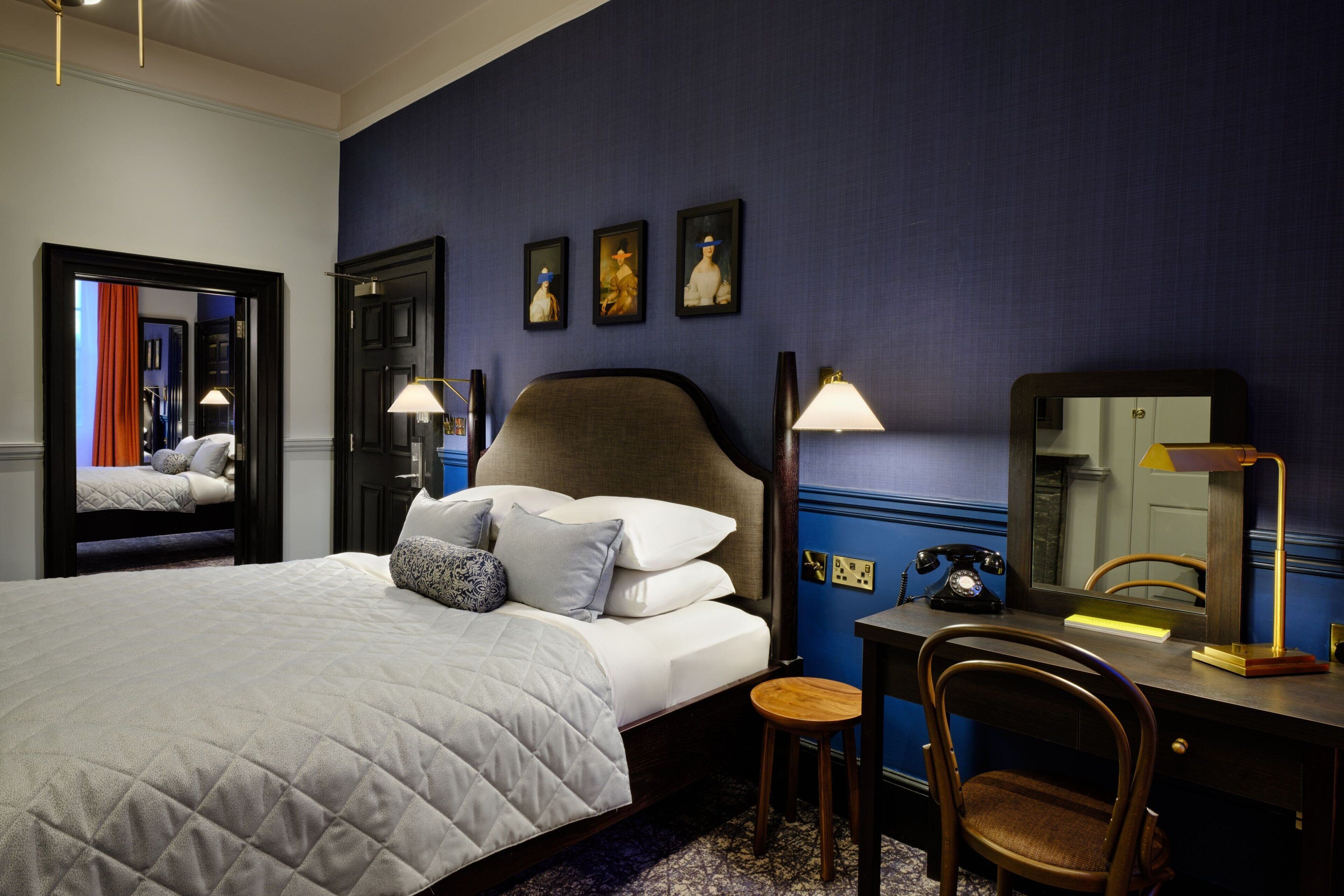 Una habitación de hotel con una cama grande, un escritorio con teléfono y una silla.