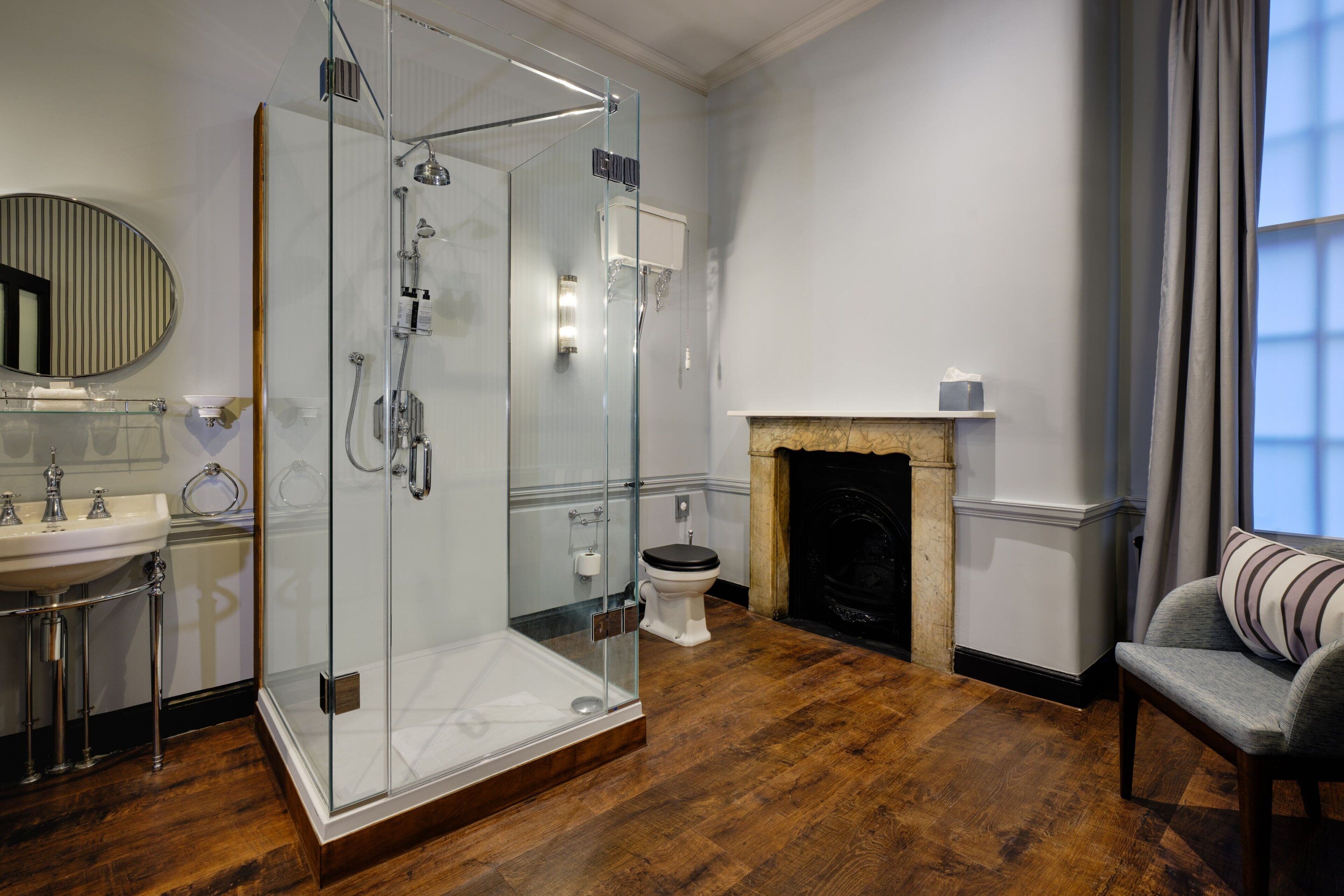 Ein modernes Badezimmer mit einer gläsernen Duschkabine, einem weißen Waschbecken und einem Kamin.