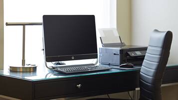 Een modern bureau met een computer, een printer en een stoel.