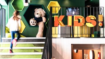 Kids can play and explore in this vibrant play area with a green wall and a fun staircase.