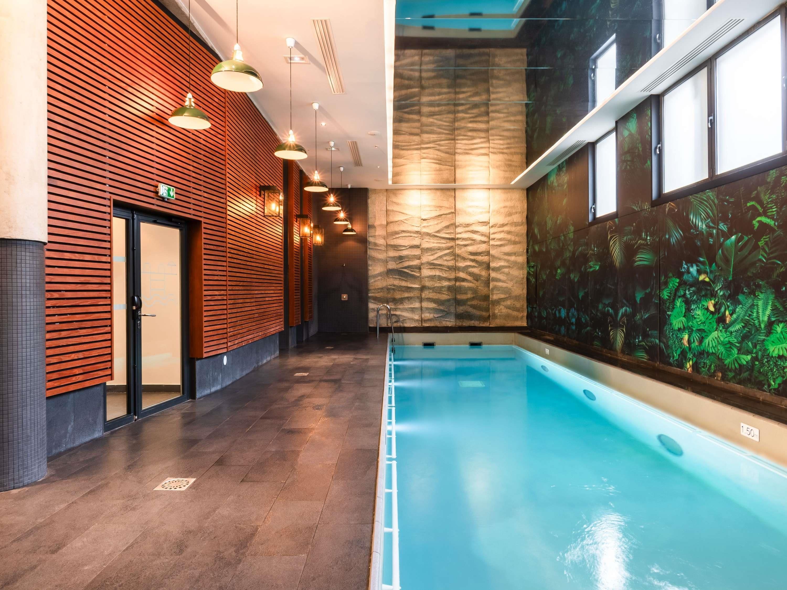 A modern indoor swimming pool with a wooden wall and a mural on the adjacent wall.