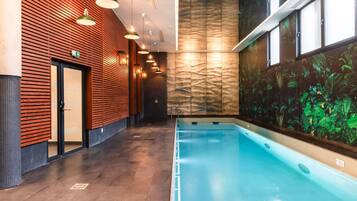 A modern indoor swimming pool with a wooden wall and a mural on the adjacent wall.