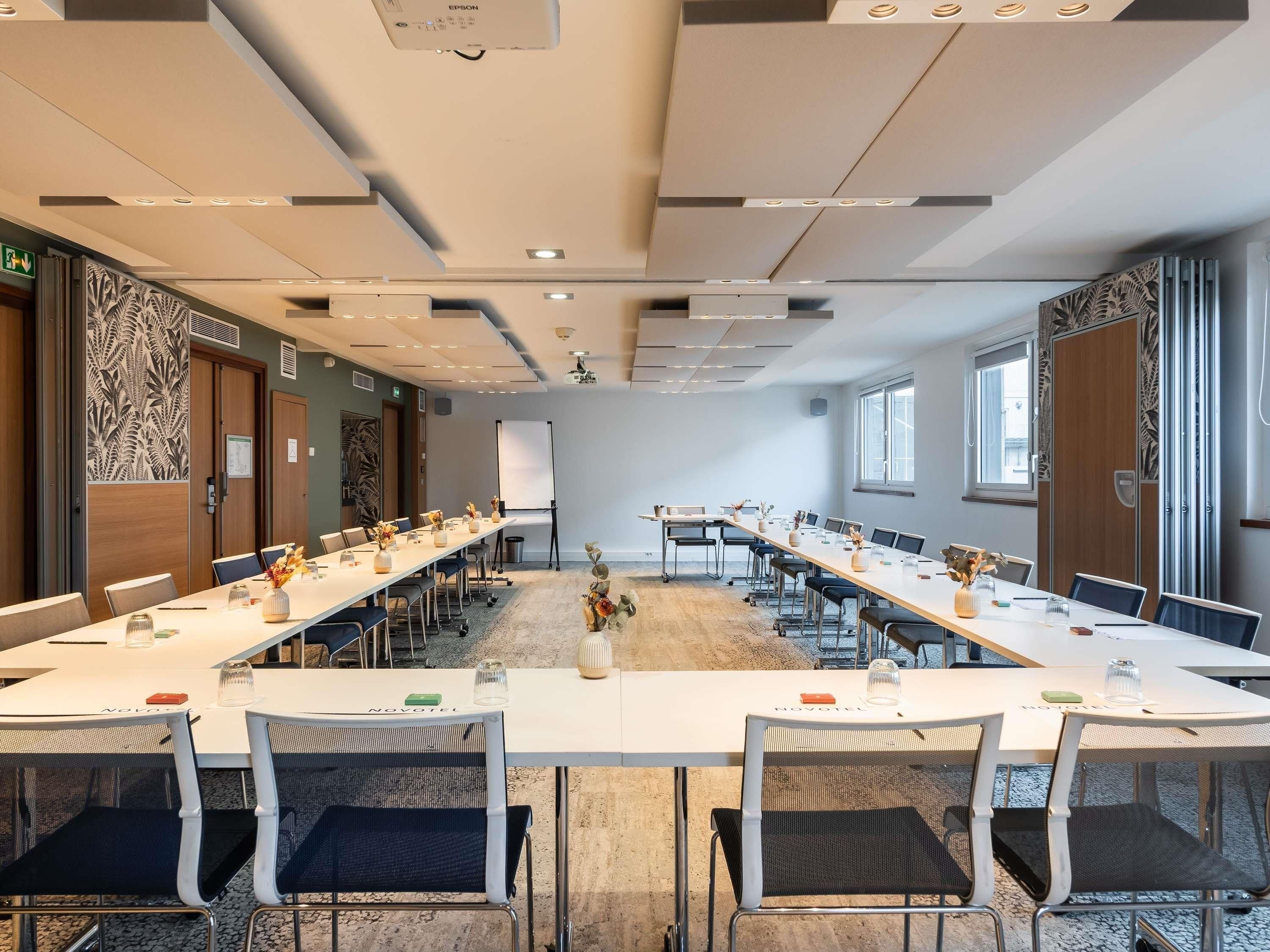 A conference room with a long table, chairs, a projector, and a whiteboard.