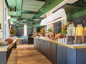 Cocina moderna con isla central, piso de madera y paredes verdes. Se observan diversos electrodomésticos y un amplio ventanal que proporciona luz natural.