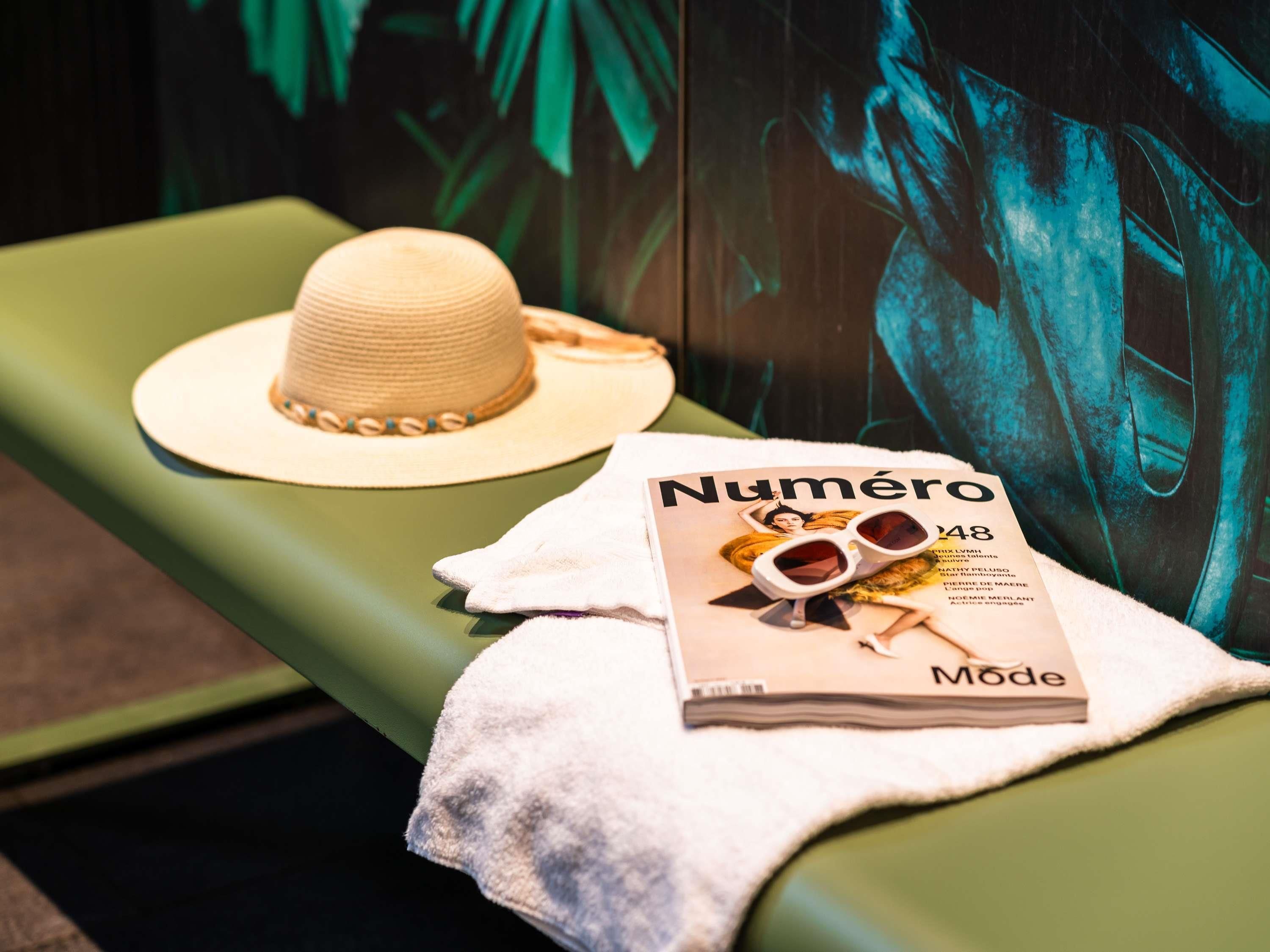 A magazine titled "Numéro Mode" on a green bench with a straw hat and sunglasses.