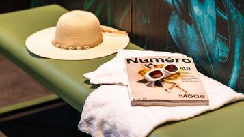A magazine titled "Numéro Mode" on a green bench with a straw hat and sunglasses.