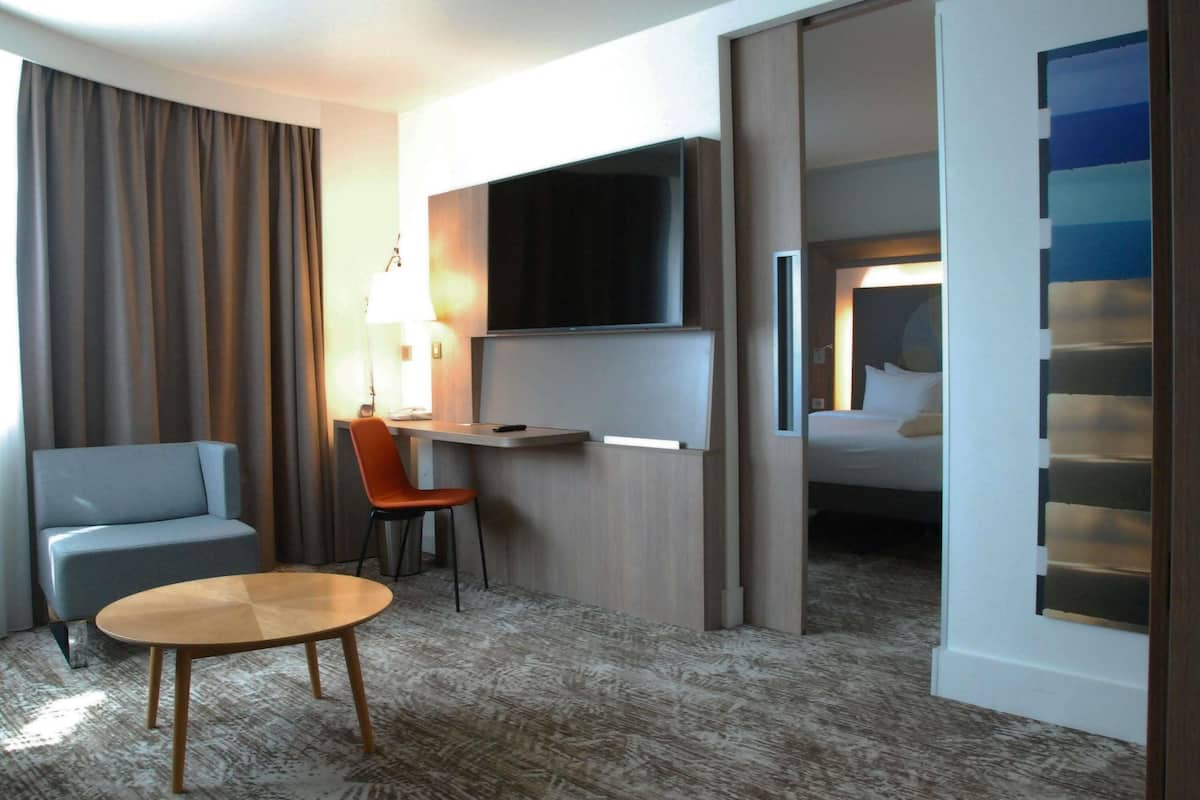 A hotel room with a bed, a TV, a desk, a chair, and a small table.