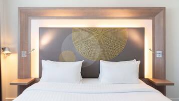 Una habitación de hotel con una cama grande, dos mesitas de noche y una obra de arte en la pared.