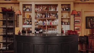 A bar area with shelves of bottles and glasses, a counter, and a vintage lamp.