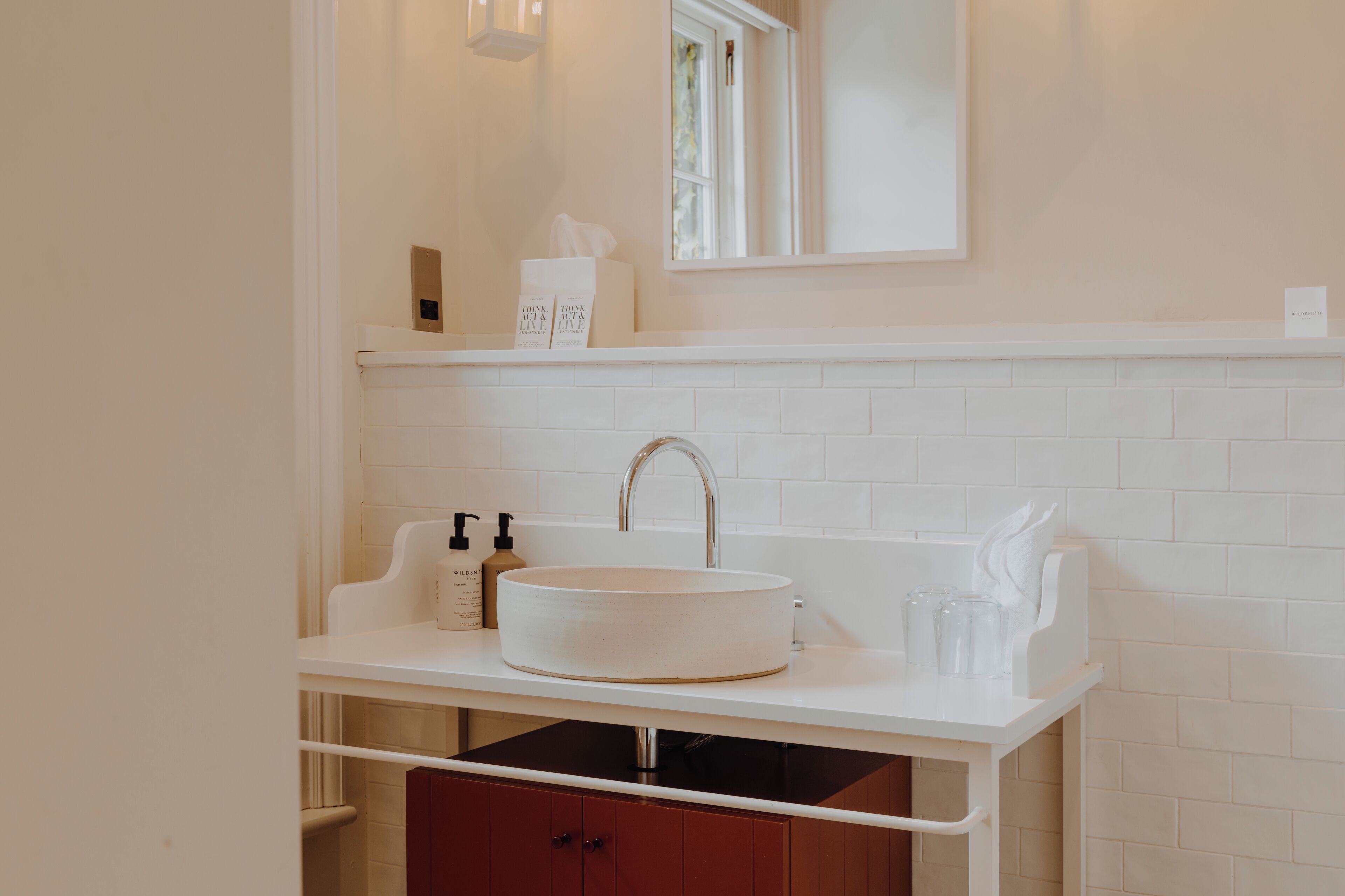 A bathroom with a white sink, a mirror above it, and a window with curtains.