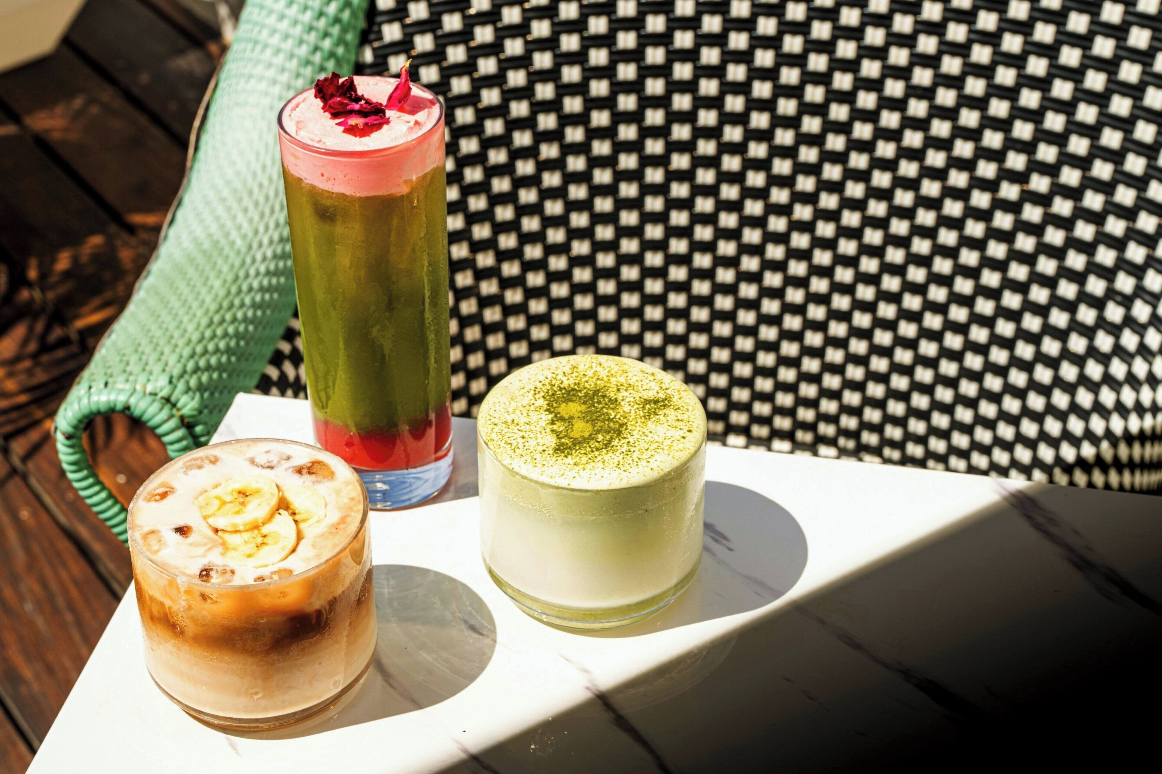 Three beverages on a table with a checkered cushion in the background.