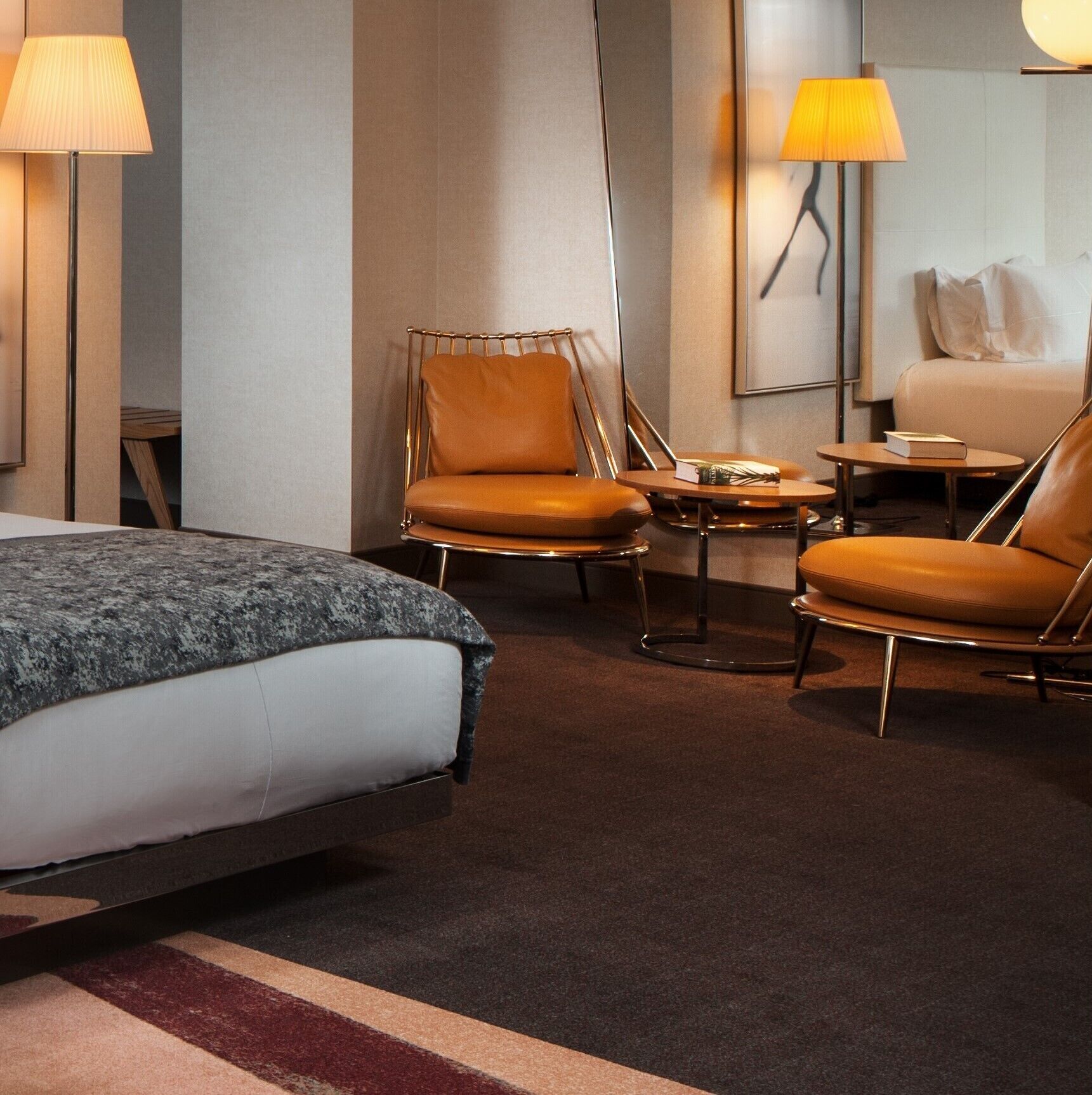Ein Hotelzimmer mit einem Bett, zwei Sesseln, einem kleinen Tisch und zwei Lampen.