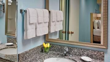 A bathroom with a granite countertop, a white sink, a mirror, and a towel rack with two towels.