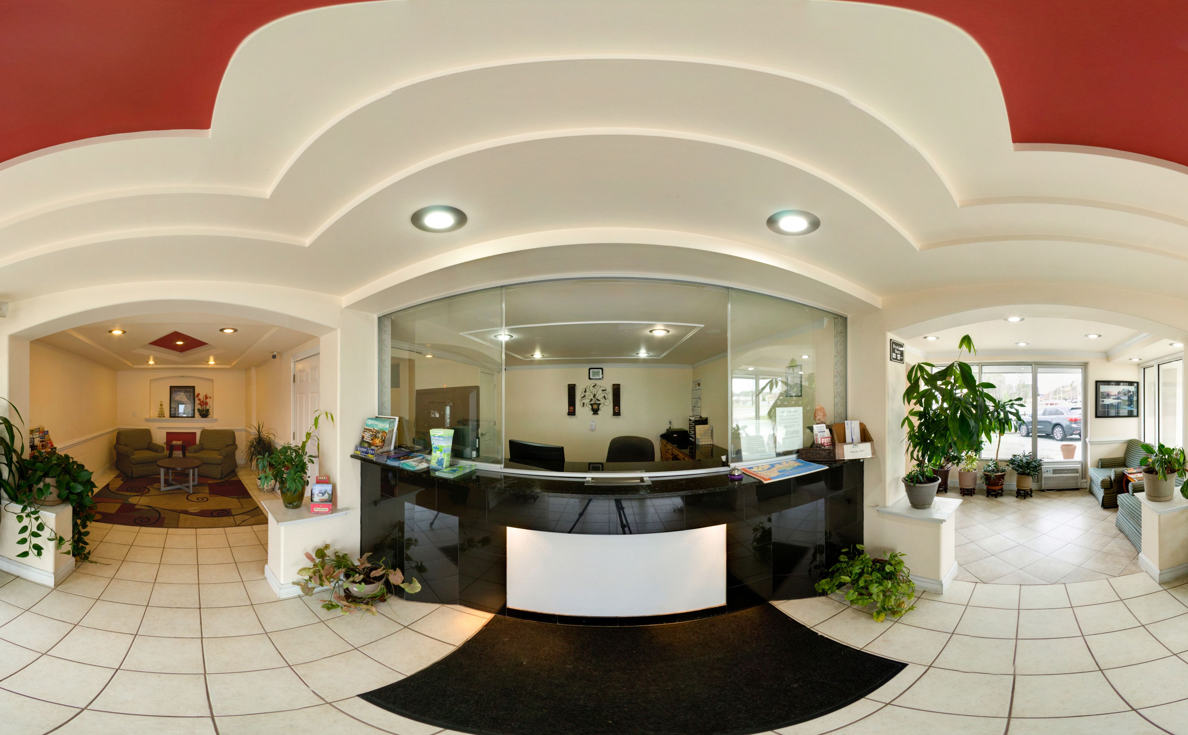 A reception area with a curved desk, seating, and potted plants.