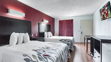 Une chambre d’hôtel avec deux lits, un bureau, une télévision et une porte.