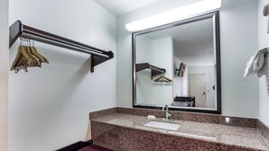A bathroom with a granite countertop, a sink, a mirror, and a towel rack. - Red Roof Inn Monteagle - I-24 (Monteagle)