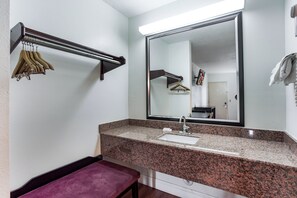 A bathroom with a granite countertop, a sink, a mirror, and a towel rack. - Red Roof Inn Monteagle - I-24 (Monteagle)