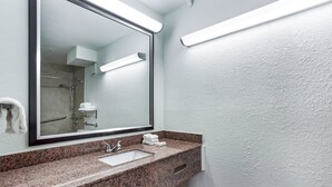 A bathroom with a granite countertop, a sink, a mirror, and a towel rack.