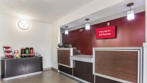 A reception area with a coffee station, a digital screen advertising free Wi-Fi, and a clock on the wall. - Red Roof Inn Monteagle - I-24 (Monteagle)