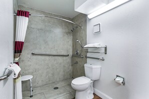 A bathroom with a shower, toilet, and grab bars. - Red Roof Inn Monteagle - I-24 (Monteagle)