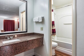 A bathroom with a granite countertop sink, a mirror, a towel rack, and a shower curtain. - Red Roof Inn Monteagle - I-24 (Monteagle)