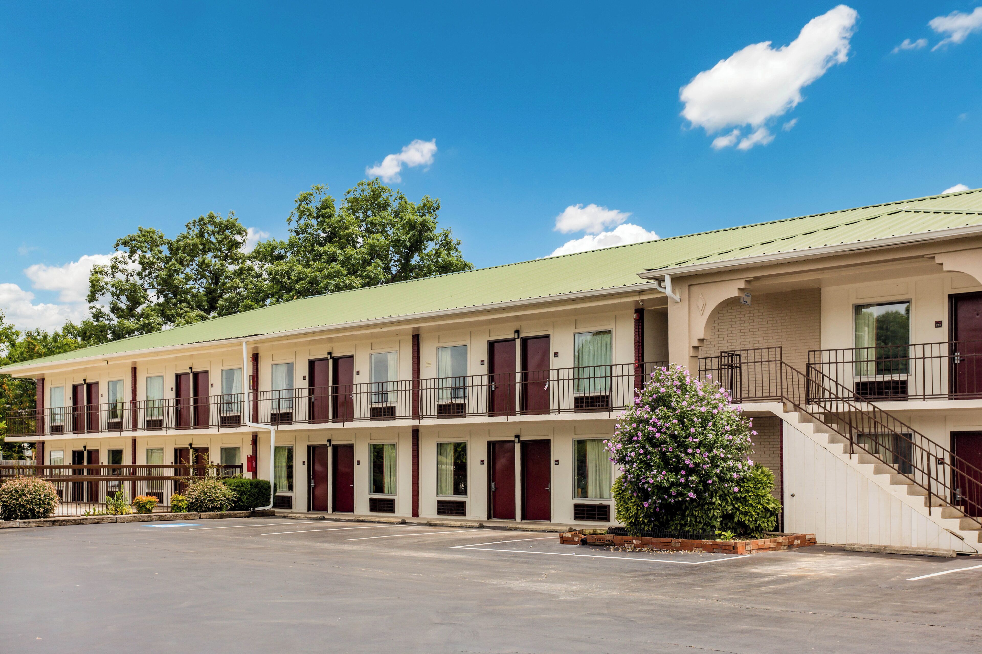 Un motel à plusieurs étages doté d’un toit végétalisé, de nombreuses chambres avec fenêtres et d’un parking.