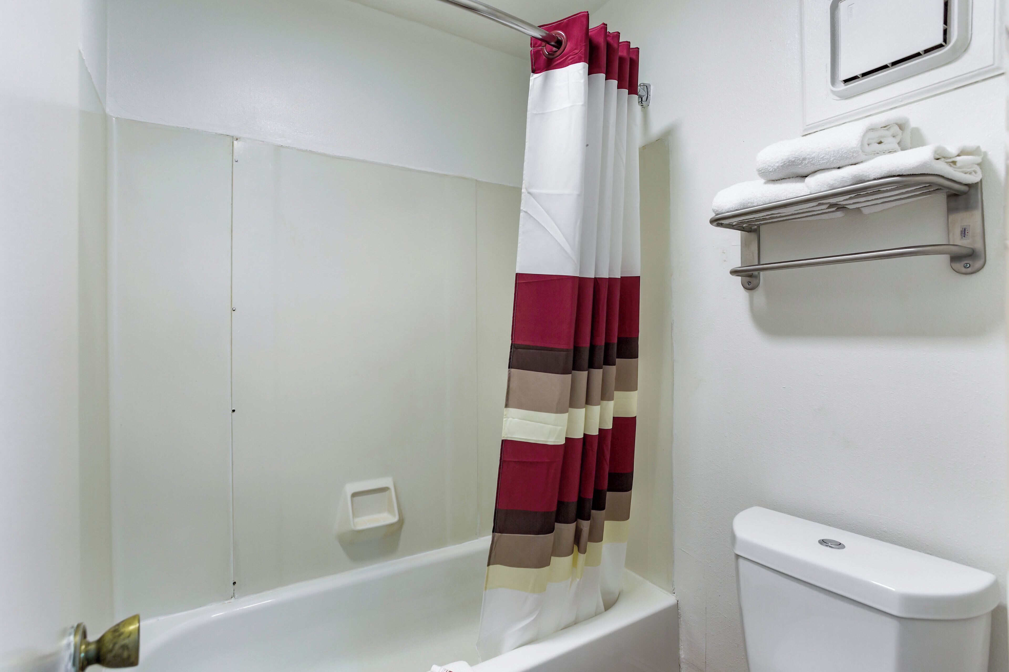 A bathroom with a shower curtain, a toilet, and a towel rack.