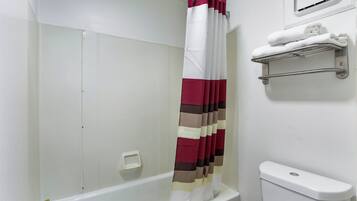 A bathroom with a shower curtain, a toilet, and a towel rack.