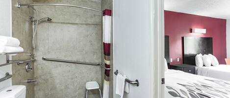A hotel bathroom with a shower, toilet, and a small stool.