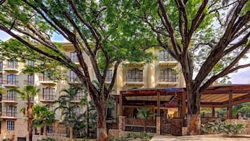 Hotel features a tree-lined entrance with a stone facade and balconies.