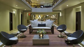 A spacious lobby with a central seating area, a coffee table with a candle, and a view of the upper floor. - Movich Casa del Alferez (Cali)
