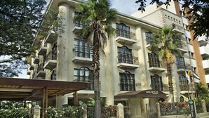 A multi-story hotel with balconies, palm trees, and a covered entrance. - Movich Casa del Alferez (Cali)