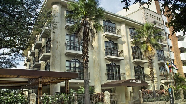 A multi-story hotel with balconies, palm trees, and a covered entrance. - Movich Casa del Alferez (Cali)