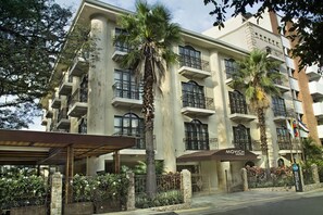 A multi-story hotel with balconies, palm trees, and a covered entrance. - Movich Casa del Alferez (Cali)