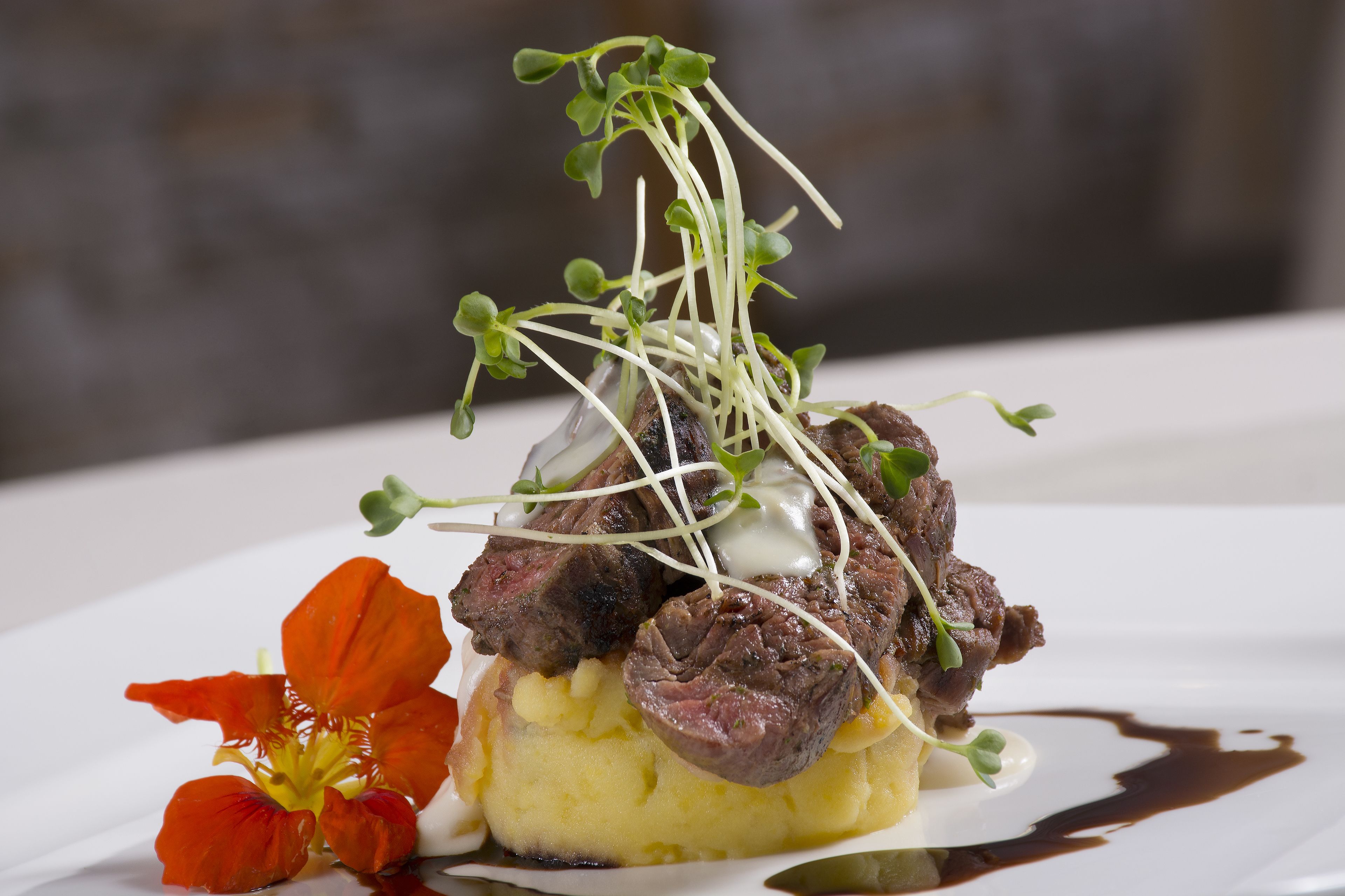 Un plat composé de viande, de purée de pommes de terre et d’une garniture de jeunes pousses.