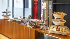 A buffet counter with various food items and a coffee station.