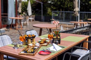 Un espacio exterior para comer con mesas, sillas y una variedad de alimentos y bebidas.