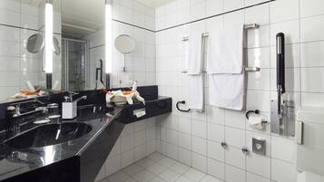 A modern bathroom with a black sink, two mirrors, a towel rack, and a toilet paper holder.