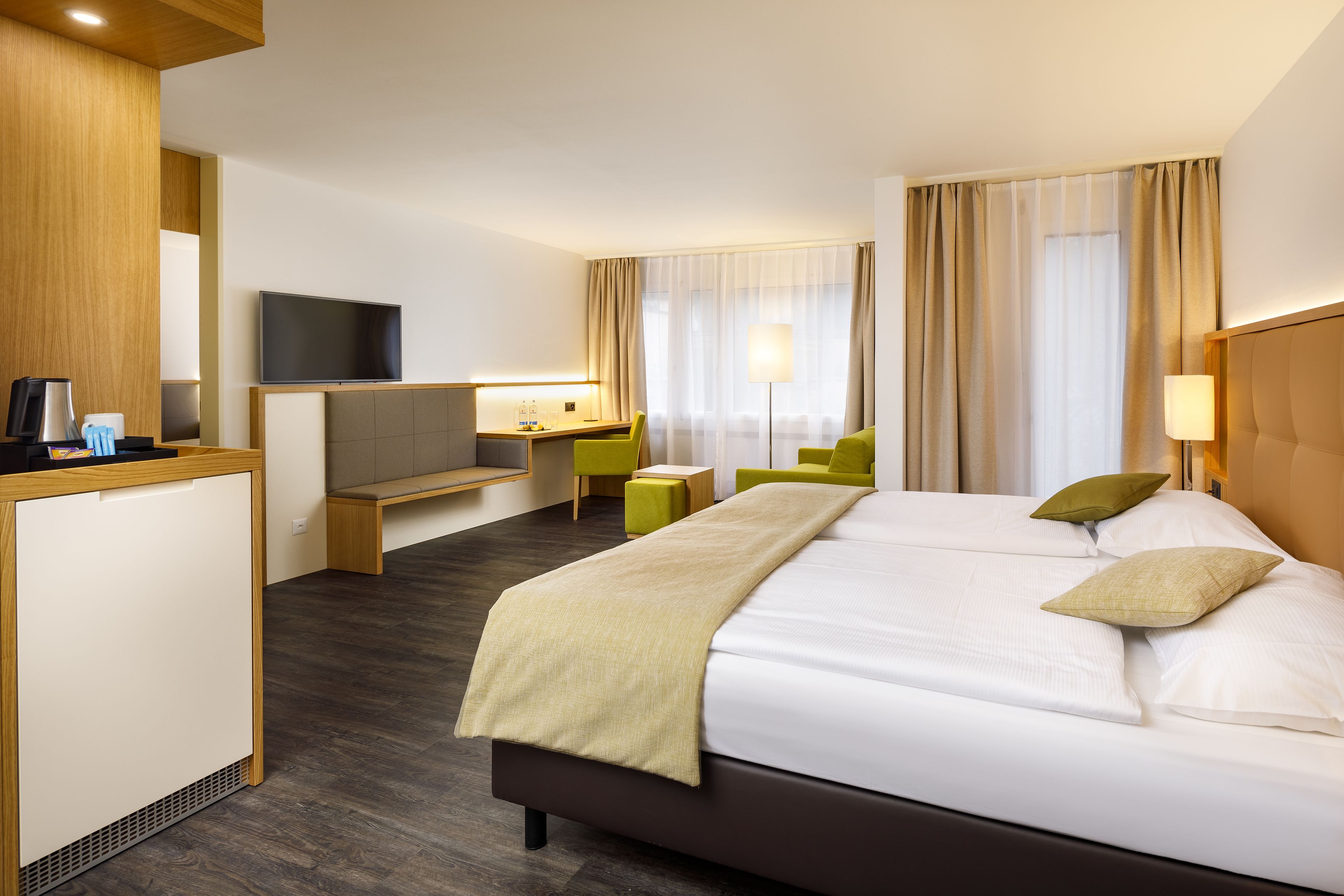 Une chambre d’hôtel comprenant un lit, un bureau, une télévision et un coin salon.