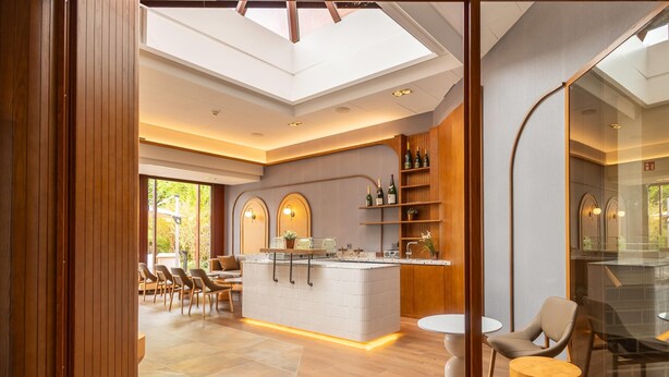 A modern kitchen with a central island, wooden cabinets, and a glass partition.