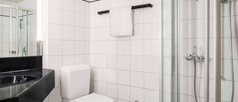 A modern bathroom with a toilet, a glass shower enclosure, and a black countertop.