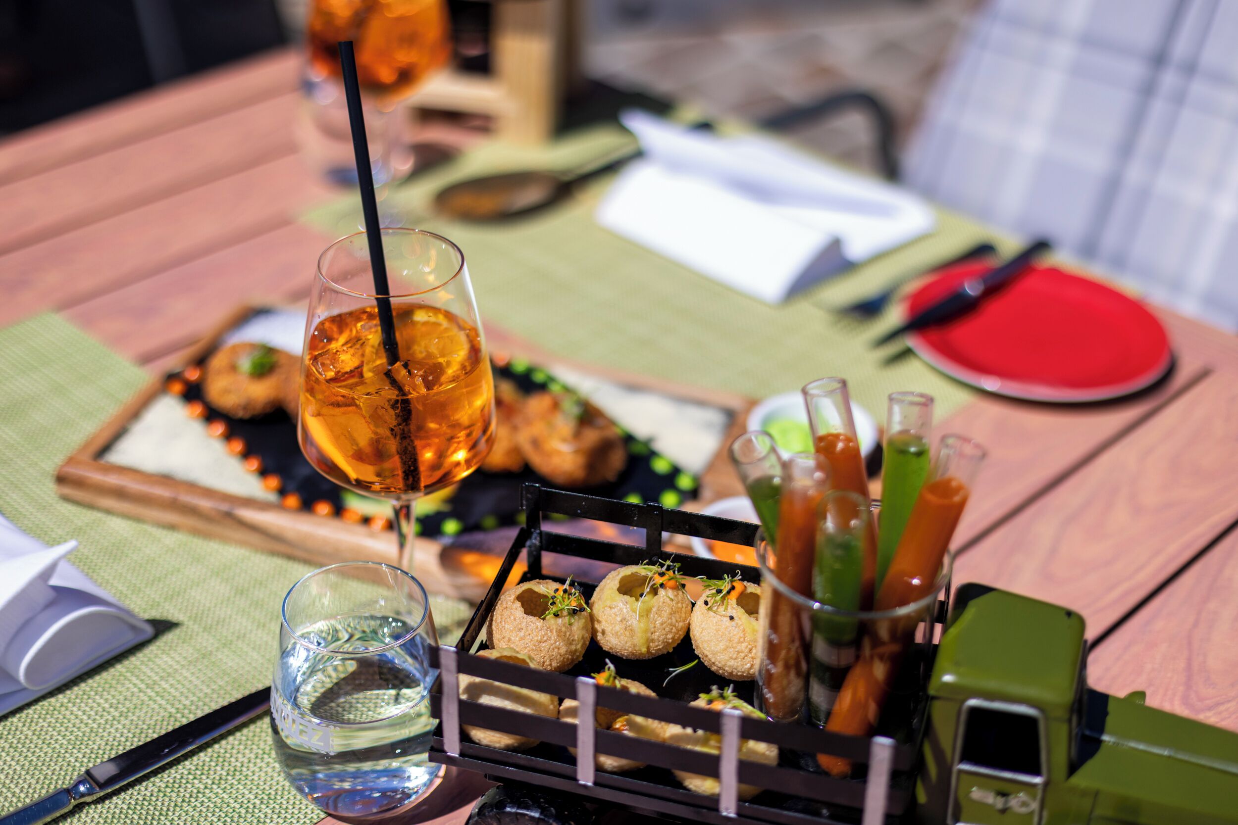 Une table à manger sur laquelle on trouve une variété d’aliments, notamment un verre de thé glacé, une assiette de hors-d’œuvre et un plateau de collations.