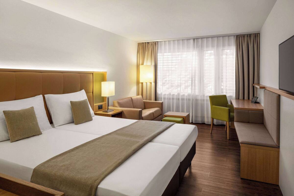 Een hotelkamer met een groot bed, een bureau, een stoel en een televisie.