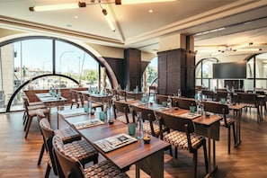 A spacious dining area with multiple tables and chairs, large windows, and a modern interior design. - Only YOU Hotel Sevilla (Seville)