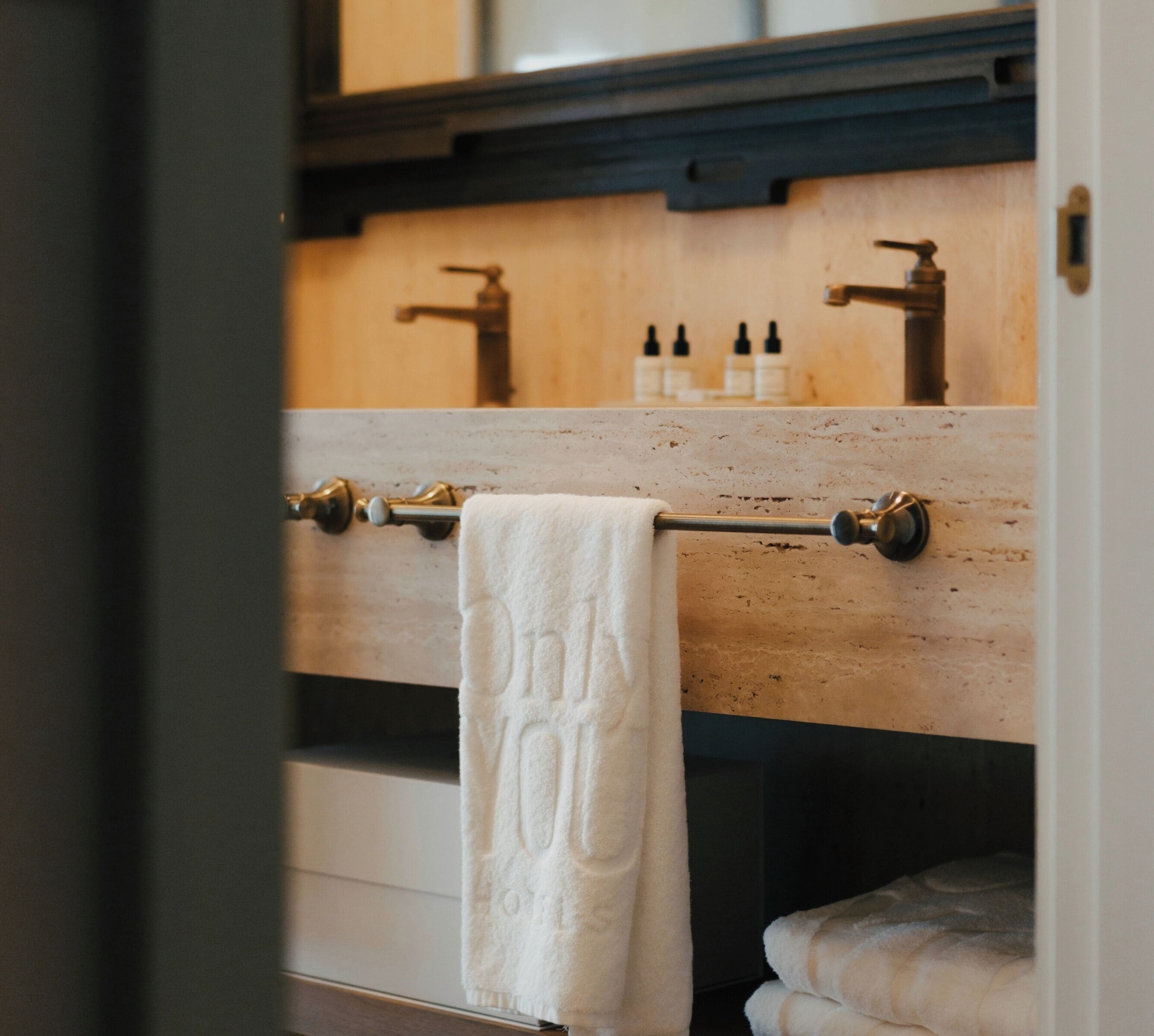 Une salle de bain avec un meuble-lavabo en bois, un porte-serviettes avec une serviette blanche et un miroir au-dessus du meuble-lavabo.