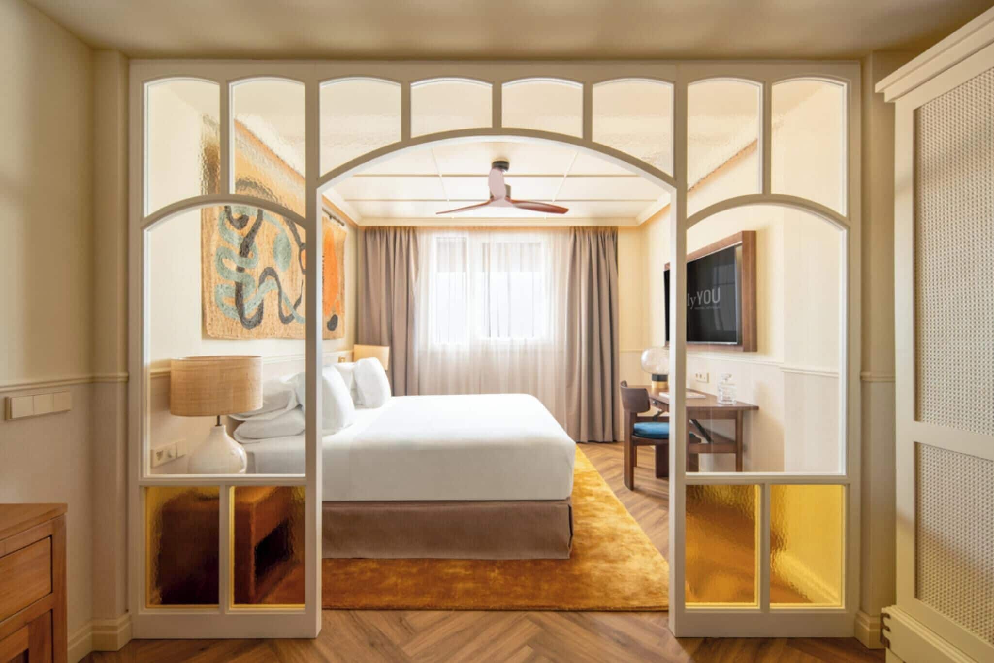 Une chambre d’hôtel avec un lit, un bureau, une télévision et un tableau au mur.