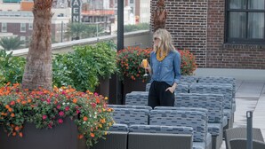 Une terrasse sur le toit, aménagée avec des meubles en osier, des plantes en pot et offrant une vue sur le paysage urbain.
