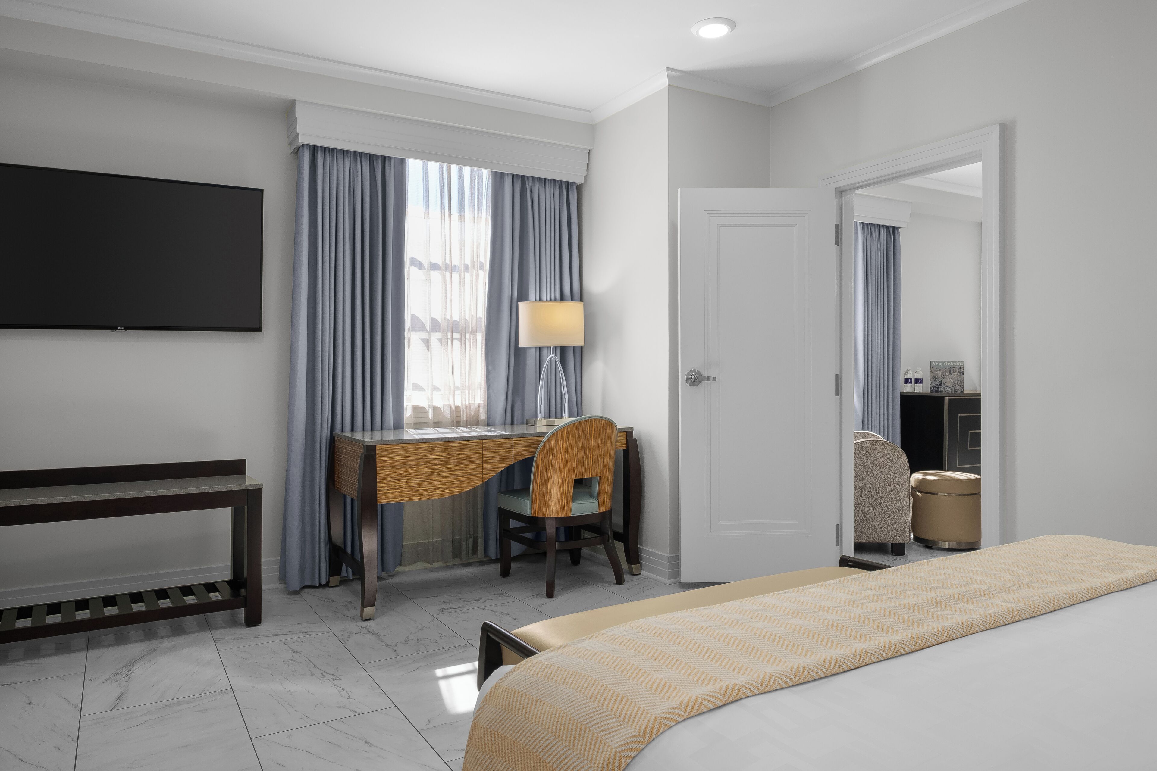 Una habitación de hotel con una cama, un escritorio con una silla, un televisor y una lámpara.
