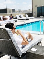 Una piscina al aire libre, sombrillas, sillones reclinables de piscina