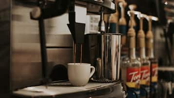 Una máquina de café sirviendo café en una taza, con botellas de licores al fondo.